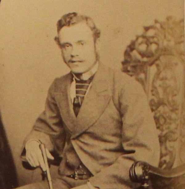 photo of a man in a pale suit sitting on an elaborately carved chair